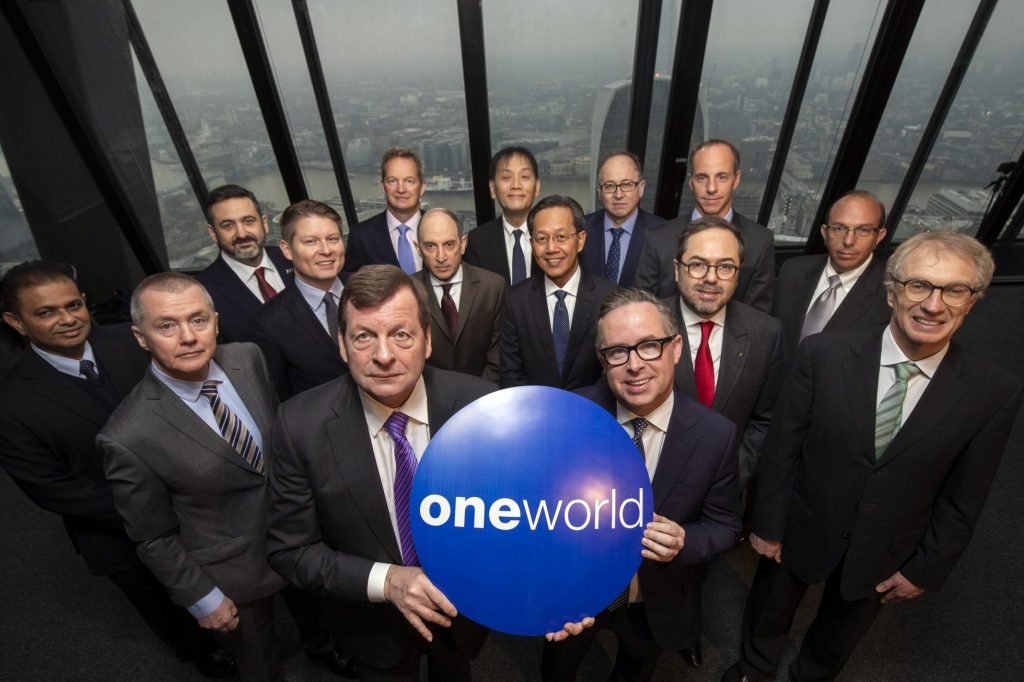 oneworld-20-years-Press-event-1FEB19-03-e15490306837401 terno, roupas, homem, Rosto humano, pessoa, sorriso, gravata, Roupa formal, Executivo, Trabalhador de escritório, posar, grupo, pessoas, em pé, outdoor