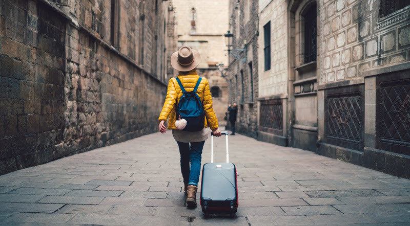 Young woman with suitcase walking at the street in Barcelona Radar PPV! Resumo das promoções de acúmulo e transferência de pontos do dia 23 de setembro de 2025
