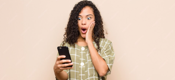 imagem de mulher surpresa com celular Entre no grupo de promoções do PPV e não perca dicas de milhas, cashback e ofertas