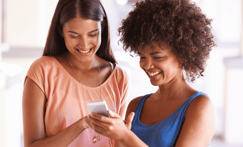 imagem duas mulheres olhando para o celular Mais milhas e mais viagens! Saiba tudo com os grupos silenciosos do PPV